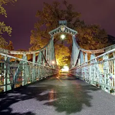 Most romantyczne miejsca opolskie to ta zabytkowa kładka nocą, oświetlona latarnią, z widokiem na drzewa i mnóstwem kłódek miłości.