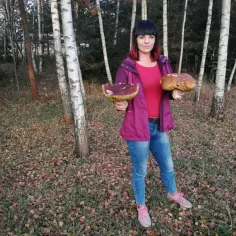 Kobieta z dwoma dorodnymi borowikami w lesie, w tle pasmo gór świętokrzyskich.
