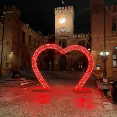 Kolobrzeg rynek nocą. Wielkie, świecące na czerwono serce na tle zabytkowego ratusza.