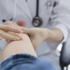 Lekarz bada skórę pacjenta, aplikując maść Clobederm na problematyczne miejsce.