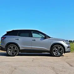 Srebrny Renault Austral na tle łąki i błękitnego nieba. Wiele osób szuka **Renault Austral opinie** przed zakupem.