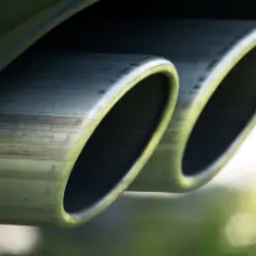 Dwa owalne końcówki wydechu samochodu, błyszczące i lekko zabrudzone. To ważny element układu wydechowego, czyli down pipe.