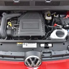 Silnik 1.0 TSI w czerwonym samochodzie, widok z góry. Widać turbosprężarkę, akumulator i płyny.