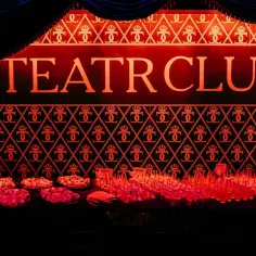 Elegancka ściana z napisem TEATR CLUB i wzorem koron. Na pierwszym planie stół z przekąskami i kieliszkami.