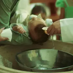 Chrzest dziecka. Dziadkowie dają prezent na chrzest. Woda kapie z muszelki na główkę niemowlaka.