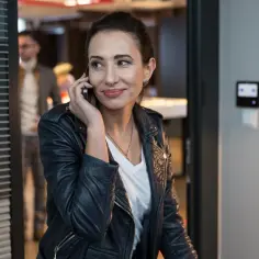 Aleksandra Popławska w skórzanej kurtce rozmawia przez telefon, jakby omawiała kolejny projekt filmowy lub serialowy.
