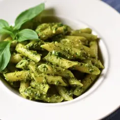 Penne z aromatycznym pesto i kawałkami pomidorów, udekorowane świeżą bazylią. Pyszne danie, które zachwyca smakiem.