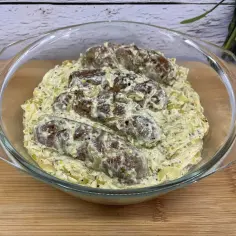 Biała kiełbasa w sosie chrzanowo-musztardowym, podana w szklanej misie. Aromatyczny sos otula soczyste kawałki kiełbasy.