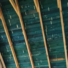 Drewniana konstrukcja dachu z zieloną membraną, na którą nałożono pianą pur.