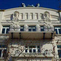 Elegancka fasada w stylu secesja z rzeźbionymi twarzami i wężami. Balkon z kutego żelaza.