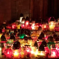 Płonące znicze, symbol modlitwy za zmarłych rodziców, tworzą ciepłe światło wśród ceglanych murów.