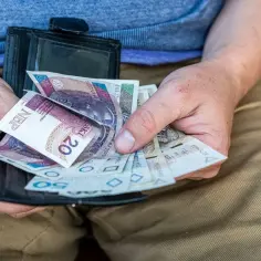 Ręce trzymają portfel z polskimi banknotami. Zastanawiam się, jak umowa zlecenie 2026 zmiany wpłyną na moje zarobki.