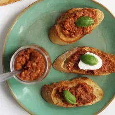 Kruche grzanki z aromatycznym, czerwonym pesto i listkami bazylii. Idealna przekąska na letnie popołudnie.