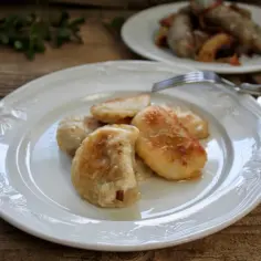 Usmażone pierogi z białej kiełbasy na białym talerzu.