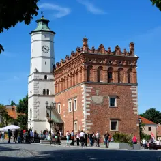 Ratusz w Sandomierzu, mieście w województwie świętokrzyskim, z ludźmi spacerującymi po rynku.