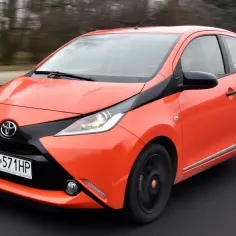 Pomarańczowa Toyota Aygo w ruchu. Zastanawiasz się, ile pali Toyota Aygo? Ten miejski samochód jest znany z niskiego spalania.