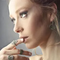 Elegancka kobieta z makijażem i biżuterią, w tym kolczyki wiszące srebrne, które dodają jej uroku.