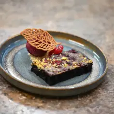 Eleganckie monoporcje: czekoladowy brownie z malinami, sorbetem i ozdobnym listkiem z ciasta.