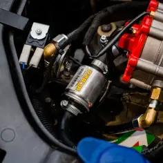 Cylindryczny element z żółtą etykietą to filtr gazu, część systemu LPG. To właśnie on odpowiada za czystość paliwa, zanim trafi ono do silnika.