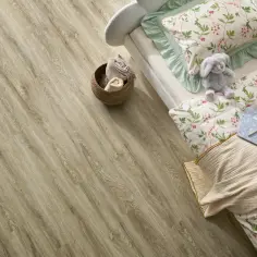 Łóżko z pluszowym królikiem i pościelą w kwiaty na podłodze z paneli winylowych. Czy panele winylowe są zdrowe? Tak, są bezpieczne dla dzieci.