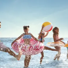 Dzieci bawią się na plaży z dmuchanymi zabawkami, idealny hotel z animacjami dla dzieci.