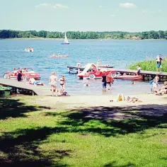 Wakacje nad jeziorem, ludzie wypoczywają na plaży i pomostach, pływają łódkami i rowerami wodnymi. Wodne atrakcje w Boszkowie przyciągają tłumy.