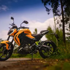 Pomarańczowy motocykl Keeway RKF 125 na tle lasu. Sprawdź keeway rkf 125 dane techniczne i poczuj wolność.