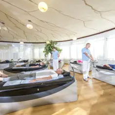 Relaks w ośrodkach rehabilitacyjnych nad morzem. Pacjenci leżą na łóżkach terapeutycznych, a personel czuwa nad ich komfortem.