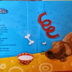 Wierszyk o piesku opowiada o jego smutkach, które znikają, gdy dostaje mleczko. Na ilustracji śpi piesek, a nad nim wiszą kości i czerwona wstążka.