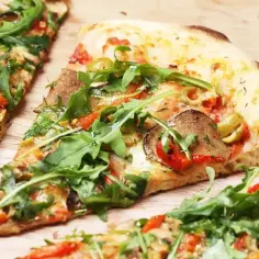 Kawałki pizzy z rukolą i warzywami. Idealna temperatura pieca pizzy to klucz do chrupiącego ciasta i rozpływającego się sera.