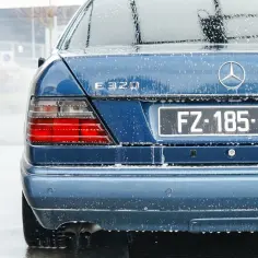 Niebieski Mercedes E320 na myjni, pokryty pianą. Pokazane tylne światła i tablica rejestracyjna FZ-185-ED. To dobry przykład, jak myć auto na myjni.