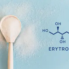 Drewniana łyżka z kryształkami i wzór chemiczny erytrytolu. Co to jest erytrytol? To słodzik.