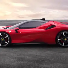 Czerwone Ferrari SF90 na torze wyścigowym, z zachodem słońca w tle.