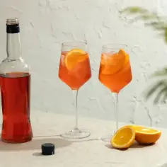 Butelka Aperolu, dwa drinki z pomarańczą i lodem, połówki pomarańczy.