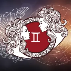 Dwie twarze patrzące na siebie, symbol **czerwiec znak zodiaku** Bliźniąt, otoczone kryształami i kołem zodiaku.