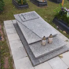 Nagrobek z granitu z imionami i datami, ozdobiony krzyżem i dwoma zniczami. Grobonet Jastrzębie Zdrój.