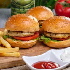 Trzy apetyczne burgery z indyka z chrupiącymi frytkami i sosami.
