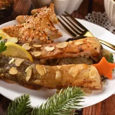Pyszny karp z grilla, podany z cytryną, migdałami i świątecznym ciastkiem w kształcie choinki.