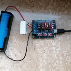 Test pojemności akumulatora 18650 za pomocą testera z wyświetlaczem cyfrowym. Widoczny niebieski akumulator, rezystor i moduł testujący.