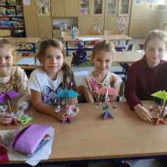 Cztery dziewczynki siedzą przy biurku i trzymają w rękach kolorowe origami.