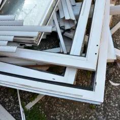 Stare okna PCV leżą na ziemi. Zastanawiasz się, co zrobić ze starymi oknami? Oto stos zużytych ram okiennych.