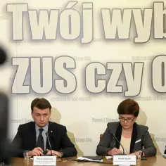 Trzech polityków siedzi przy stole. Na ścianie za nimi widnieje napis "Twój wybór ZUS czy OFE".