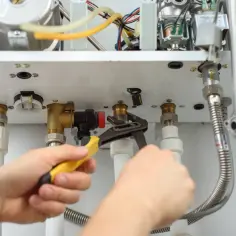 Serwisant dokręca kluczem instalację gazową w mieszkaniu, zgodnie z przepisami.