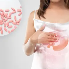 Kobieta z bólem brzucha, obok tabletki. Inhibitory pompy protonowej bez recepty pomogą złagodzić dolegliwości.