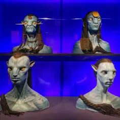 Busty Na'vi z filmów Jamesa Camerona, z niebieską skórą i żółtymi oczami, prezentowane na niebieskim tle.