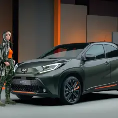 Stylowa kobieta obok zielonego Aygo X. Czy to auto spełnia **toyota aygo opinie**? Nowoczesny design i miejski charakter.