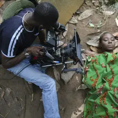 Reżyser z kamerą RED filmuje aktorkę leżącą na ziemi, tworząc kolejną scenę dla **nollywood**.