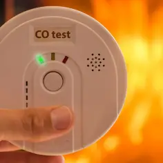 Dłoń trzyma czujnik czadu z napisem "CO test" i zieloną diodą. Sprawdź, jak przetestować czujnik czadu, by zapewnić bezpieczeństwo.