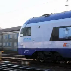 Pędzący pociąg PKP Intercity z napisem "Stadler" na tle budynku.