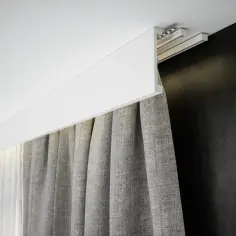 Nowoczesna maskownica do ledów nad szarymi zasłonami, tworząca subtelne oświetlenie sufitowe.